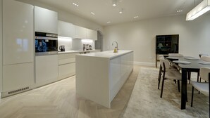 Une cuisine moderne avec des meubles blancs, un îlot central et un coin repas comprenant une table et des chaises.