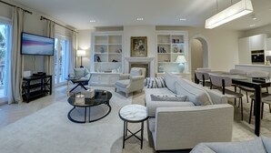 Un salon moderne comprenant un canapé, des fauteuils, une table basse et un coin repas avec une table et des chaises.