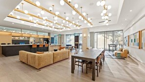 A spacious living area with a wooden dining table, sofas, and a kitchen area with a bar.
