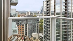 A balcony with wicker furniture, a view of high-rise buildings, and a clear sky.