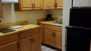 A kitchen with wooden cabinets, a black refrigerator, a coffee maker, and a laptop on the counter. - "the Sweet", close to downtown, beaches, parks, colleges, airports & hospitals. (Jacksonville)