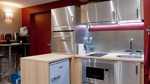A compact kitchen with stainless steel appliances, a built-in oven, and a small refrigerator. - Very Nice Studio Ideal For 2 Near The Halles (Avignon)
