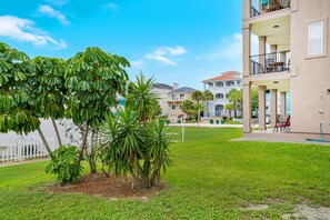 A residential area with a grassy lawn, a white fence, and a building with a balcony.