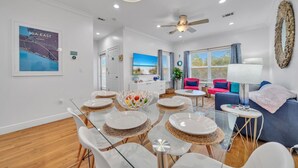 A modern living room with a dining area, a ceiling fan, and a large window with a view of the sea. - ⭐200yds2Beach~Beach Access~4 Bikes~2Pools~The Coastal Gem (Santa Rosa Beach)