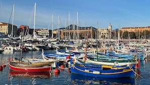 A marina with numerous boats docked, surrounded by buildings and clear skies.