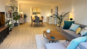 A modern living room with a sofa, coffee table, and a dining area with chairs and a table.