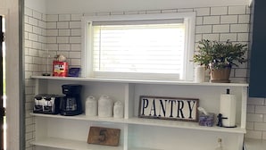 A white pantry shelf with labeled jars for coffee, sugar, and tea, a coffee maker, and a number 5 sign. - Entire Home with Lakeview (L'Anse)