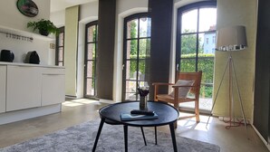 A modern kitchen with a dining area, large windows, and a view of greenery outside. - Charming rear building near the old town (Osnabrück)