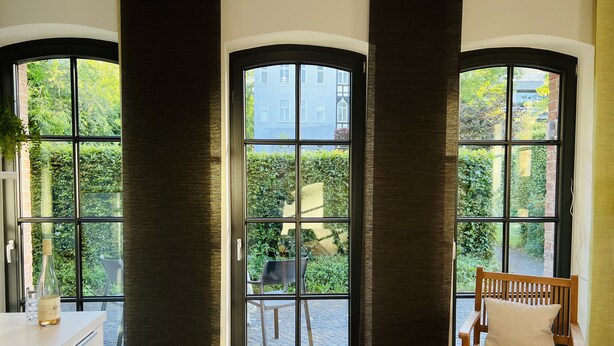 A room with large windows, a wooden chair, and a white cabinet. - Charming rear building near the old town (Osnabrück)