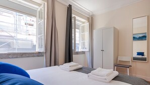 Habitació d'hotel amb un llit, un armari, una taula i una finestra amb cortines.