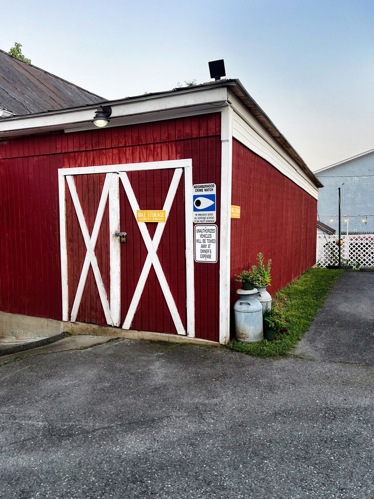 A red building with a white door, a bike storage sign, and a Neighborhood Crime Watch sign.