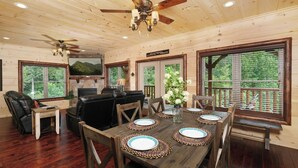 A wooden interior with a dining table set for four, surrounded by leather chairs. - Quittin Time - Hot Tub, Game Room & Home Theater (Gatlinburg)