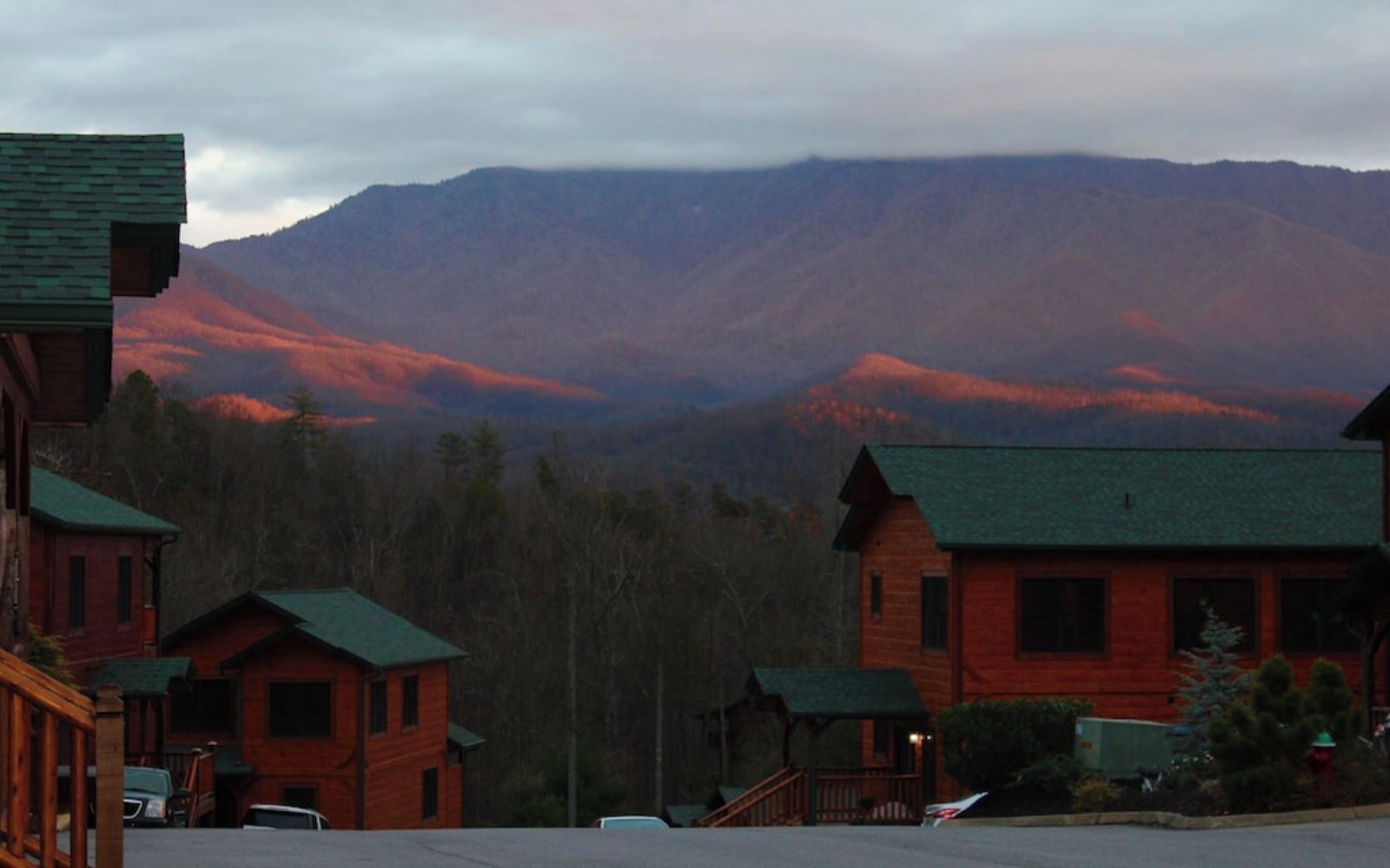 A row of wooden cabins with a mountain backdrop.