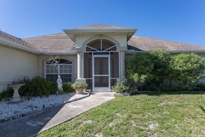 Stylish single-story home with a pitched roof, flanked by a small porch and surrounded by a well-manicured lawn.