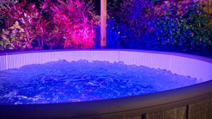 A hot tub surrounded by plants and illuminated by colorful lights. - Remarkable 3-bed Hot Tub House in Blackpool (Blackpool)