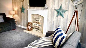 A living room with a fireplace, a flat-screen TV, a lamp, and decorative stars. - Remarkable 3-bed Hot Tub House in Blackpool (Blackpool)