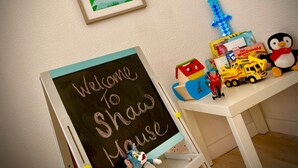 A chalkboard with "Welcome to Shaw Mouse" written on it, a framed picture of "Kids Corner", and various children's toys and books on a shelf. - Remarkable 3-bed Hot Tub House in Blackpool (Blackpool)
