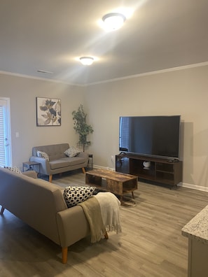 Una sala de estar con un sofá, una mesa de centro, un televisor y una planta.