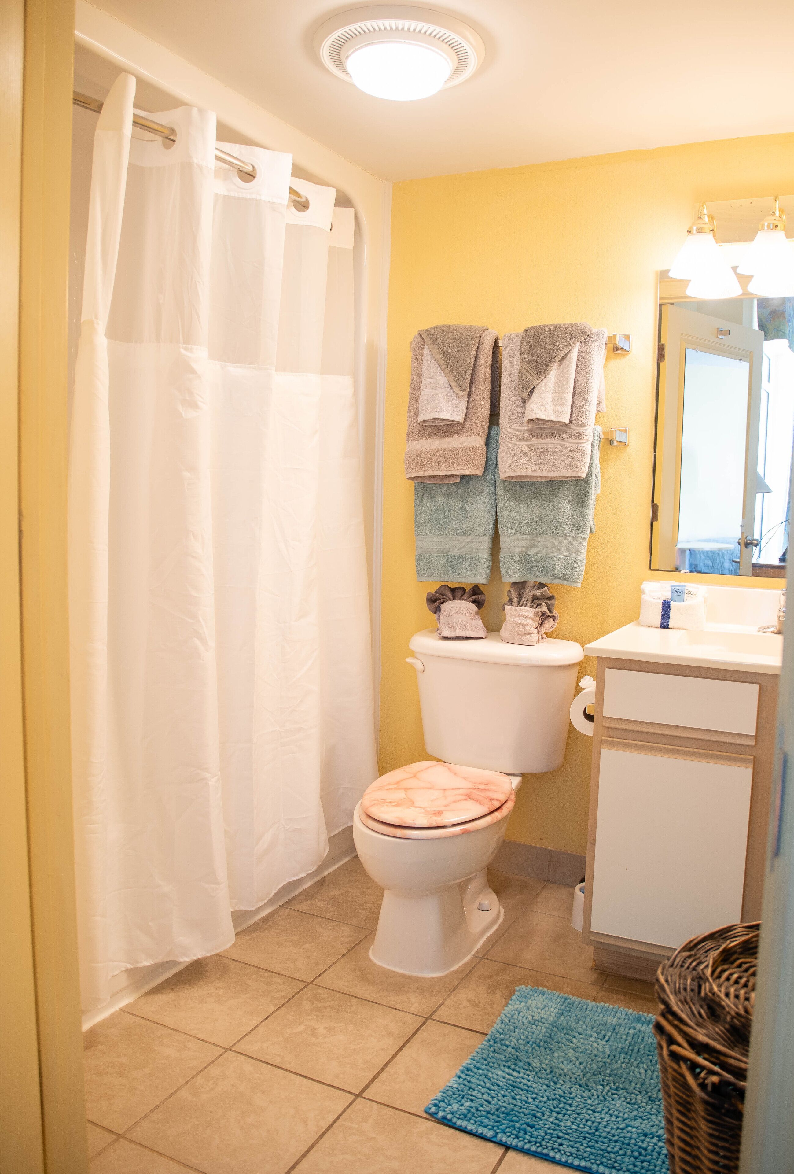 A bathroom with a toilet, a sink, a mirror, and a shower curtain.