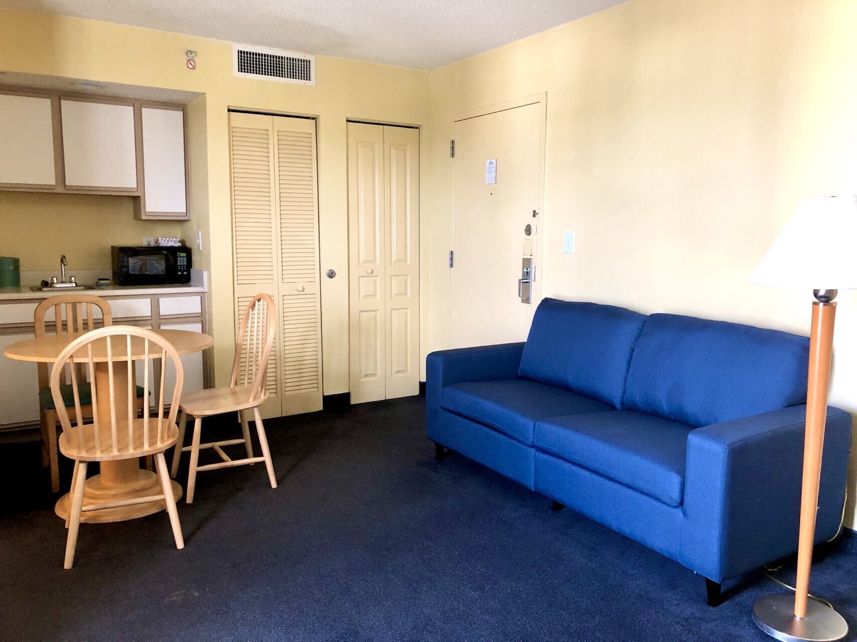 A compact living space with a kitchenette, a blue sofa, and a dining area with wooden chairs.