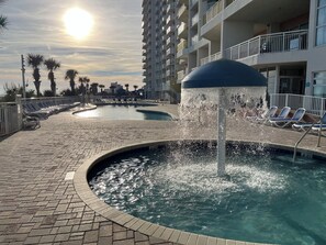 A pool area with a water fountain, sunlit sky, and lounge chairs. - Lovely oceanview studio in Bay Watch Resort North Myrtle Beach (North Myrtle Beach)