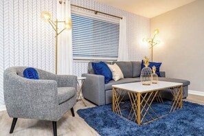 Relax in this stylish living room with a grey sofa, armchair, and blue shag rug.