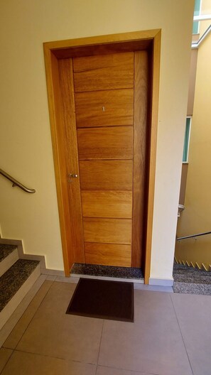 Uma porta de madeira com o número '1', um puxador de metal e um tapete de entrada.