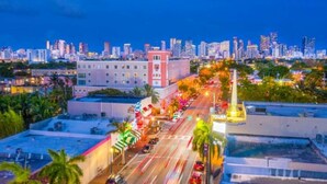 A cityscape at dusk with a prominent building with a pink facade and a tall tower. - Miami Suite 203 (Miami)