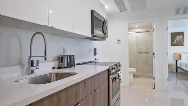 A modern kitchen with a double sink, a microwave, and a stove. - Miami Suite 203 (Miami)