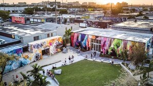 An urban building with a large mural on the side, a grassy courtyard, and surrounding streets. - Miami Suite 203 (Miami)