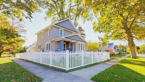 A two-story house with a white picket fence, a front porch, and a well-maintained lawn.