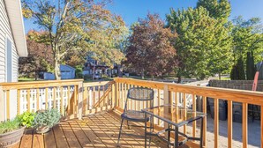 A wooden deck with a glass table and metal chair, surrounded by a wooden railing.