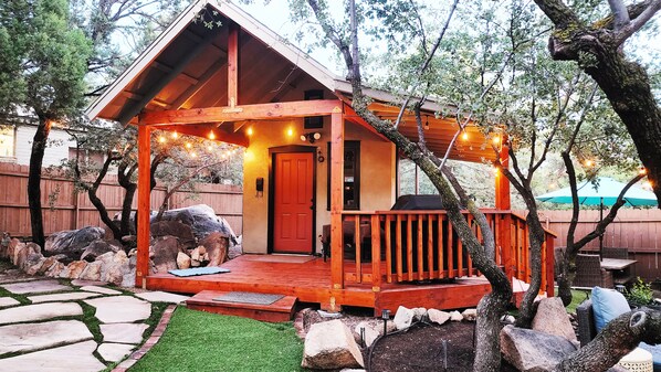 A wooden cabin with a porch, a door, and string lights.