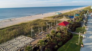 A beachside hotel with a boardwalk, beach access, and outdoor seating areas. - Ocean View Condo,  Steps to Beach & Boardwalk, 3BR/2BA! ★★★★★   (Carolina Beach)