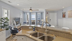 A modern kitchen with granite countertops, stainless steel sinks, and a ceiling fan. - Ocean View Condo,  Steps to Beach & Boardwalk, 3BR/2BA! ★★★★★   (Carolina Beach)