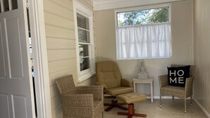 A room with two wicker chairs, a small table with a Buddha statue, and a window with white curtains. - Remodeled Vintage Private Home. <5 min to UF and Downtown (Gainesville)