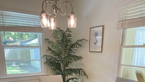 A dining area with a round wooden table, four upholstered chairs, a potted plant, and a chandelier. - Remodeled Vintage Private Home. <5 min to UF and Downtown (Gainesville)