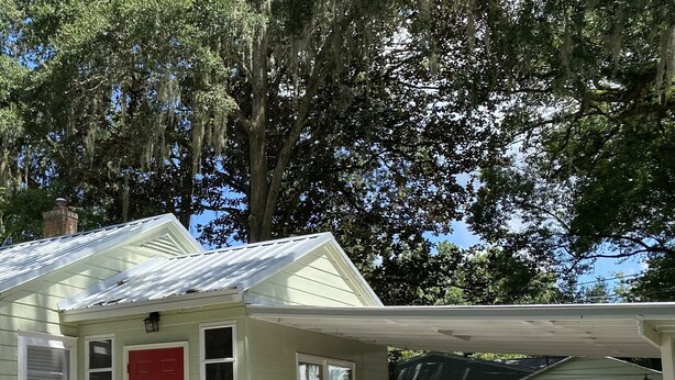 A small, single-story house with a white picket fence, a red door, and a covered porch. - Remodeled Vintage Private Home. <5 min to UF and Downtown (Gainesville)