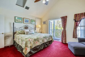 A bedroom with a bed, a red carpet, a balcony with curtains, and framed pictures on the wall. - Shared Pool + Gallery Art | Walk to Duval + Southernmost | Duval Sea Turtle (Key West)
