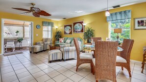 A spacious living area with a ceiling fan, wicker furniture, and a dining table. - Shared Pool + Gallery Art | Walk to Duval + Southernmost | Duval Sea Turtle (Key West)