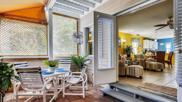 An open-plan living area with a dining table and chairs, a ceiling fan, and a view into the kitchen. - Shared Pool + Gallery Art | Walk to Duval + Southernmost | Duval Sea Turtle (Key West)