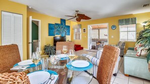 A dining area with a table set for four, a ceiling fan, and a sofa in the background. - Shared Pool + Gallery Art | Walk to Duval + Southernmost | Duval Sea Turtle (Key West)