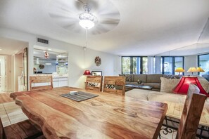 Una sala de estar moderna con una mesa de comedor de madera, un sofá y un ventilador de techo.
