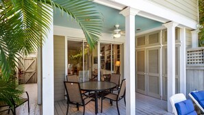 Eine überdachte Terrasse mit rundem Tisch, Stühlen, Deckenventilator und Blick ins Haus.
