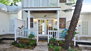 A two-story house with a front porch, stone pathway, and a tree. - Tranquility by AvantStay | Close to Duval St w/ BBQ & Shared Pool (Key West)