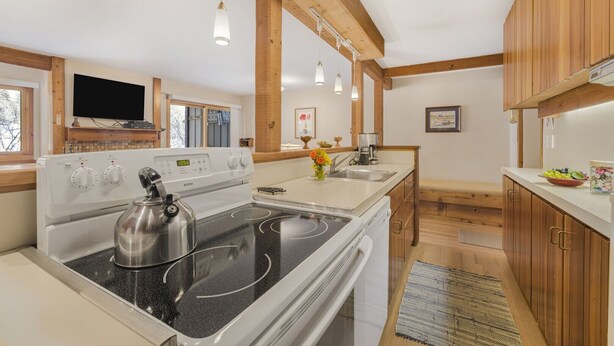 A modern kitchen with a stove, sink, and wooden cabinets. - RMR: Juniper 112 Condo in The Aspens/Wilson,WY (Wilson)