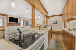A modern kitchen with a stove, sink, and wooden cabinets.