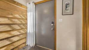 A wooden wall with a grey door, a framed picture, and a power outlet on the wall. - RMR: Juniper 112 Condo in The Aspens/Wilson,WY (Wilson)