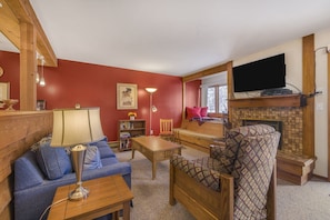 Relax in this inviting living room with a sofa, armchair, and fireplace, perfect for unwinding with a good book.