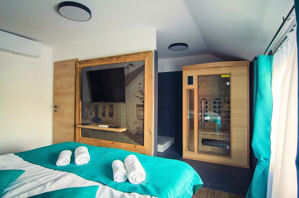 A hotel room with a bed, a wooden cabinet, a glass shower enclosure, and a mirror.